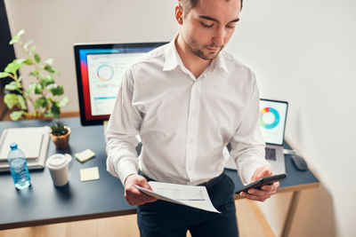 Portrait of young man using mobile phone in office