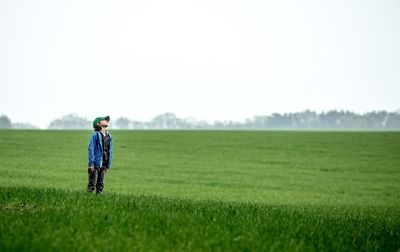 Full length of man standing on field against clear sky