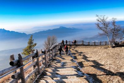 People looking at mountain landscape against blue sky