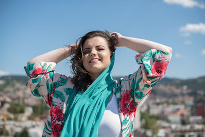 Smiling young woman against sky