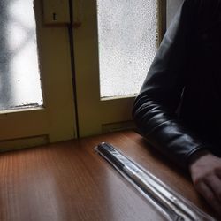 Low section of man on table by window at home
