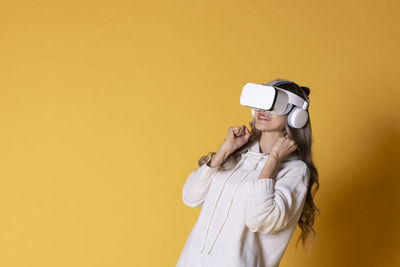 Rear view of young woman standing against yellow background