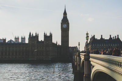 Low angle view of big ben by bridge over river against sky