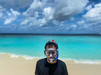 Portrait of man standing at beach against sky