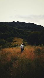 Rear view of woman walking on mountain against sky