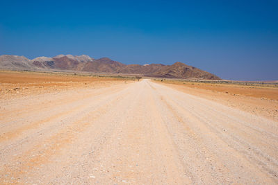 Scenic view of desert against clear blue sky