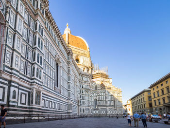 People in front of historic building against sky in city