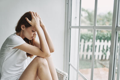 Frustrated woman sitting by window