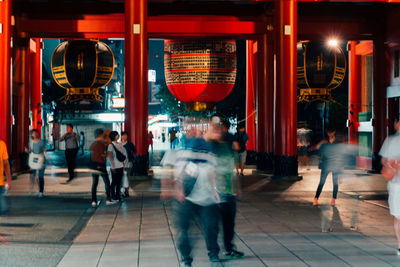 People walking on illuminated street at night