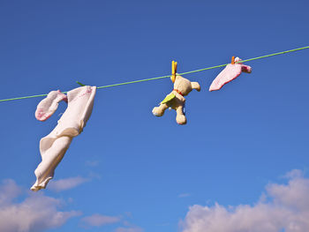 Low angle view of clothespins hanging on rope against blue sky