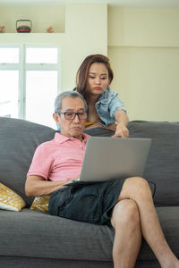 Full length of a woman using phone while sitting on sofa