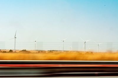 A field of wind turbines on road against clear sky, shot while travelling on the autobahn.