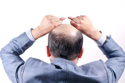 Rear view of man holding hands against white background