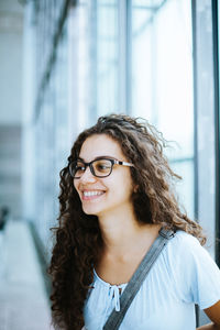 Close-up of beautiful smiling woman against window