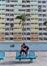 Full length of man photographing against building in city