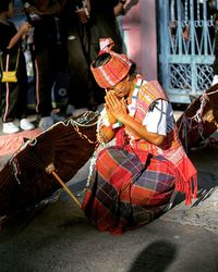 Woman praying by chinese umbrella on ground during festival