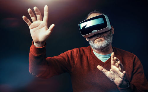 Senior man using virtual reality headset against black background