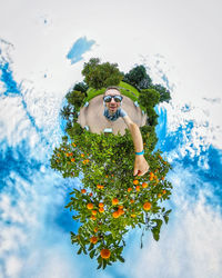 Man standing by flowering plant against sky