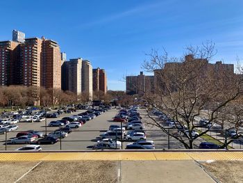 Vehicles on road by buildings in city against sky