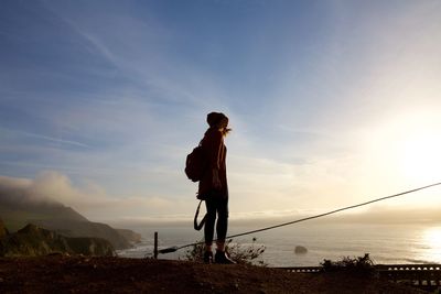 Low angle view of woman standing by sea against sky