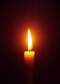 Close-up of lit candle against black background