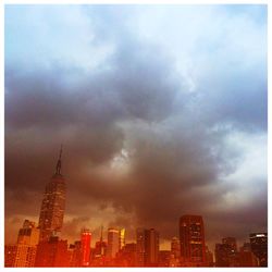 Low angle view of skyscrapers against cloudy sky