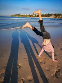 Shadow of people on beach with a boy doing handstand 