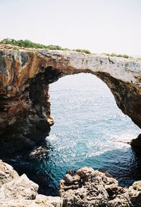 Rock formations by sea against clear sky