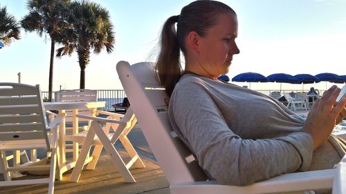 Woman sitting on chair at table against sky