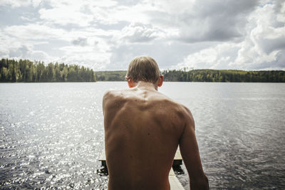 Rear view of shirtless man standing in water