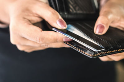 Close-up of woman inserting credit card in wallet
