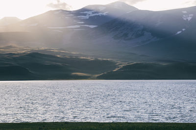 Scenic view of sea by mountains against sky