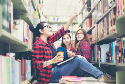 Full length of young woman reading book