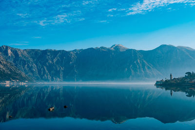 Scenic view of lake and mountains against blue sky