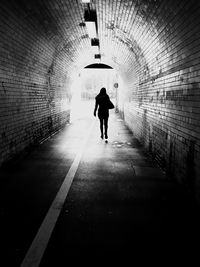 Rear view full length of woman walking in tunnel