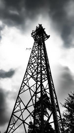 Low angle view of silhouette communications tower against sky