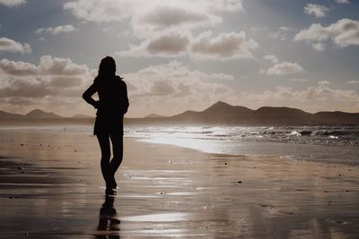 Silhouette woman standing on beach against sky