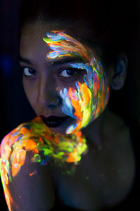 Close-up portrait of young woman with paint on face and shoulder