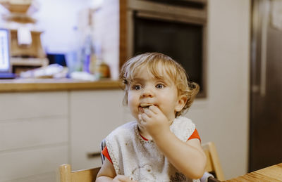 Portrait of cute girl eating food on table at home