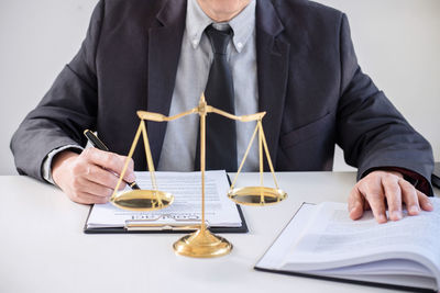 Midsection of judge sitting at table against white background