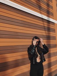 Full length of woman standing against brick wall