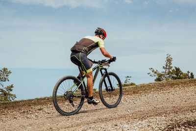 Low angle view of man riding bicycle on field against sky