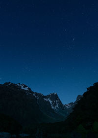 Low angle view of snowcapped mountains against starry sky at night