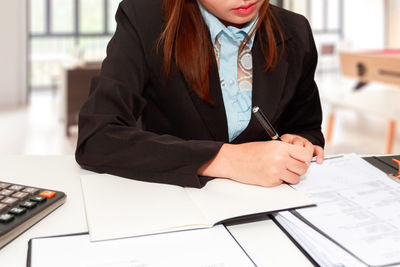 Midsection of businesswoman working at desk in office