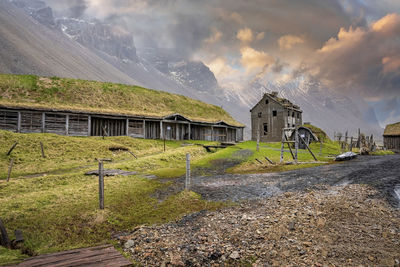 Traditional houses on grassy field in viking village against sky at sunset