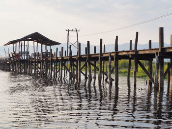 Wooden posts on pier over sea against sky