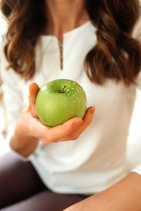 Midsection of woman holding apple