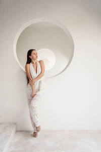 Young girl with long hair in full growth in white clothes on a white background