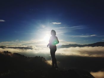 Full length of silhouette young woman standing on mountain against sky