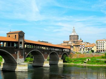 Arch bridge over river against buildings